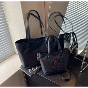 Detalle del juego de bolsos de nailon negro con bordado rojo y herrajes dorados
