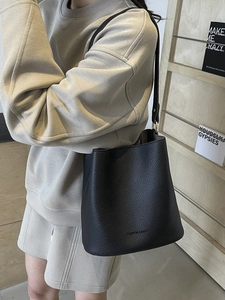 Minimalistische schwarze Beuteltasche mit Kieselmaserung für Damen mit Schultergurt und Logo