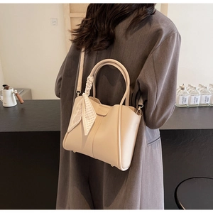Detail of beige bucket bag with polka dot scarf handle and adjustable strap