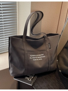 Large dark grey canvas tote bag with white letter print and external pocket for daily commute