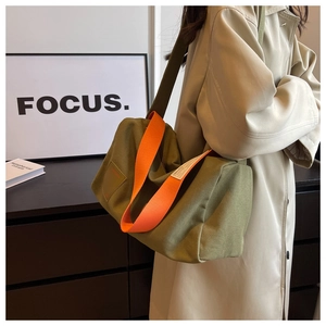 Detail of green canvas tote bag with orange handles and wide adjustable shoulder strap