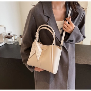 Detail of a beige tote bag with a decorative silk scarf and adjustable shoulder strap