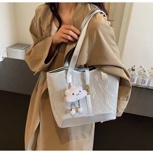 Silver wrinkled tote bag with white plush cloud charm and golden lock detail close-up
