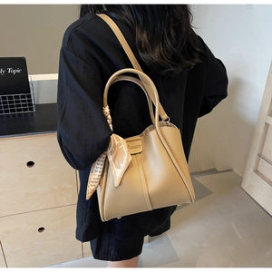 Detail of khaki bucket bag with decorative silk scarf and metal feet on the bottom
