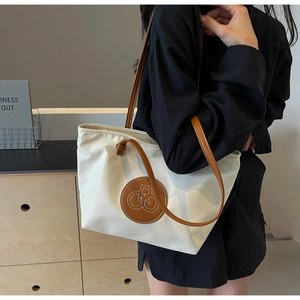 Detalle del bolso tote de nailon blanco con asas de cuero marrón al hombro