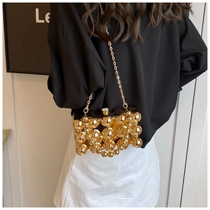 Detail of luxury gold beaded hard-shell box bag with metallic spheres and chain strap