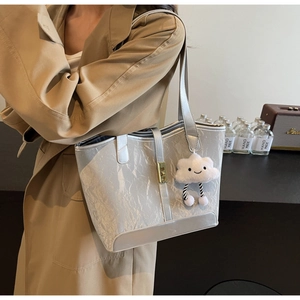 Detail of silver pleated tote bag with golden twist lock and white cloud plush charm