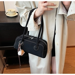 Detail of black canvas Boston bag with white stitching and decorative baseball charm