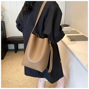 Brown leather bucket bag with pebble texture and adjustable shoulder strap on a model