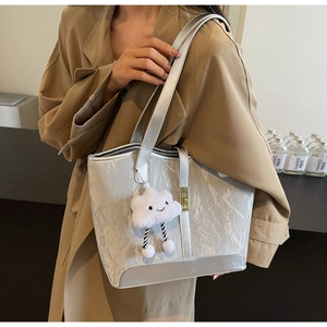 Detail of silver metallic tote bag featuring crinkled texture and cloud plush charm