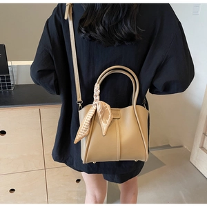 Detail of khaki bucket bag with decorative silk scarf and adjustable leather strap