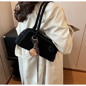 Detail of black canvas shoulder bag with white contrast stitching and baseball pendant