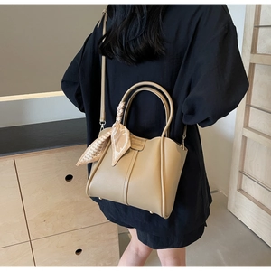 Detail of beige leather bucket bag with silk scarf handle and adjustable shoulder strap