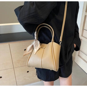 Detailed shot of beige leather bucket bag with houndstooth scarf and adjustable strap