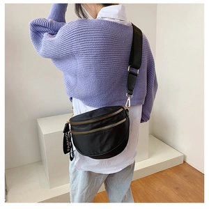 Fashionable black nylon half-moon crossbody bag with golden zippers and wide strap