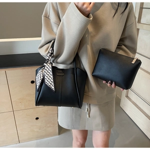 Detail of black leather bucket bag with decorative scarf and matching zipper pouch
