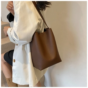 Detail of dark brown leather bucket bag showing grainy texture and fashion brand lettering