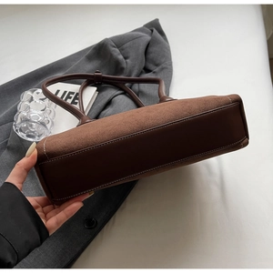 Detail of vintage brown suede and leather baguette bag with reinforced stitching