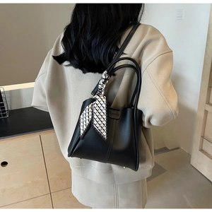 Detail of a black leather bucket bag with a checkered silk scarf wrapped handle