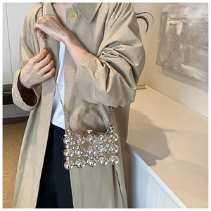 Detail of silver acrylic sphere clutch bag worn with a stylish trench coat