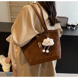Detail of brown vintage tote bag with pebble texture, metal clasp and plush cloud charm