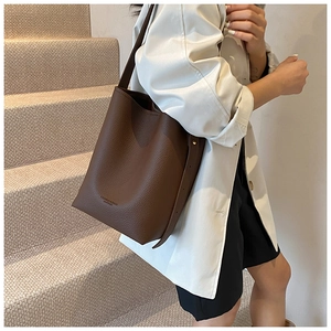 Detail of dark brown leather bucket bag with pebble texture and adjustable shoulder strap