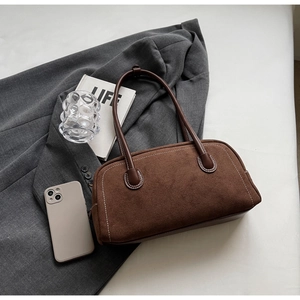 Detailed view of dark brown frosted suede shoulder bag with contrast stitching on a suit