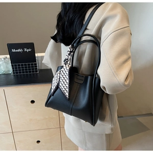 Detail of black matte tote bag with geometric silk scarf tied on handle