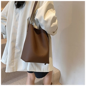 Detail of dark brown pebble leather bucket bag showing soft texture and shoulder strap