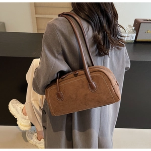 Detail of brown suede shoulder bag showing white contrast stitching and long leather handles