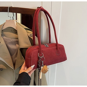 Close-up of matte wine red Boston bag with embossed logo and baseball glove charm