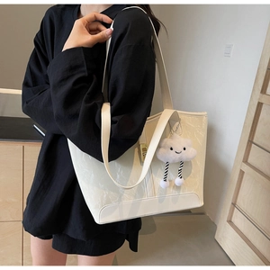 Detail of cream tote bag with marble texture and a plush cloud charm on a black outfit