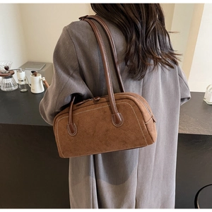 Detailed side view of vintage brown suede baguette bag with contrast stitching on model