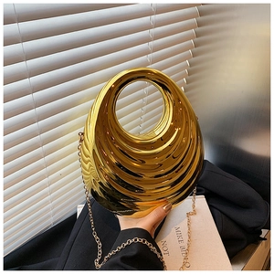 Close-up of golden teardrop evening bag with wavy metal texture and chain strap