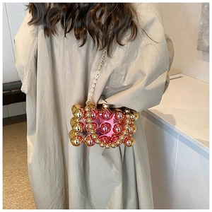 Detail showing pink and gold metallic spherical beads and chain of the evening clutch bag