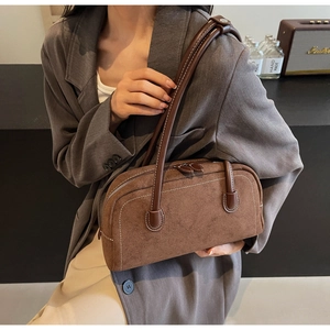 Close-up of brown matte suede shoulder bag featuring white contrast stitching and double zippers