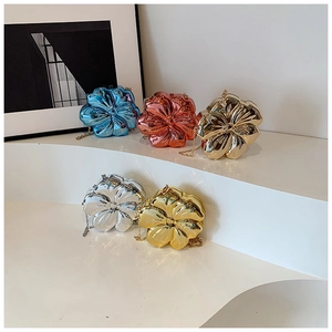 Five metallic flower-shaped clutch bags with chain straps displayed on a white podium