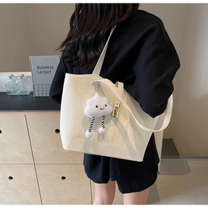 Detail of off-white tote bag with glossy wrinkled texture and plush cloud charm