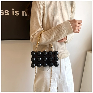 Detail of black acrylic evening bag with 3D sphere texture and golden bead handle