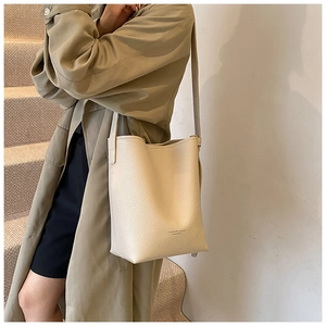 Detail of cream leather bucket bag showing lychee grain texture and printed logo