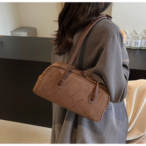 Detailed view of brown matte baguette bag with white contrast stitching and slim strap