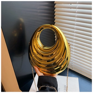 Detail of gold acrylic clutch with wave texture and round hollow metal handle