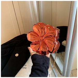 Macro detail of 3D rose gold flower evening clutch with polished metallic finish and chain