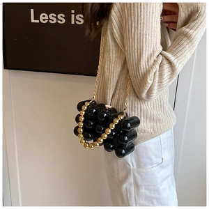 Detail of capsule-shaped acrylic evening bag with gold beaded handle and chain strap