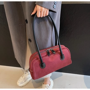 Detail of burgundy frosted leather baguette bag with white stitching and double zippers