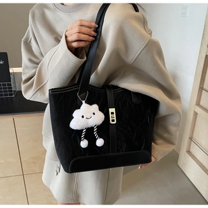 Detail of black pleated tote bag with gold buckle and cute cloud plush charm accessory