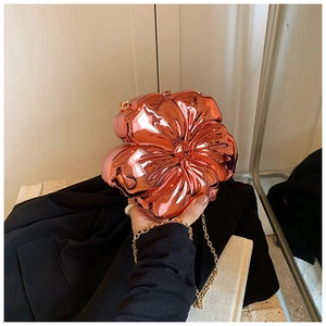 Close-up of rose gold floral evening bag with metallic petals and a golden chain strap