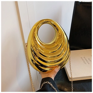 Detail of gold hard-shell evening bag with wavy texture and circular ring handle