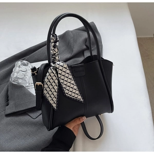 Detail of black leather bucket bag with geometric silk scarf and adjustable strap