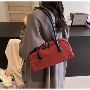 Detail of burgundy suede underarm bag showing white stitching and dual zipper closure